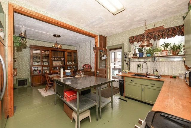 kitchen featuring a sink, wallpapered walls, open shelves, and green cabinetry