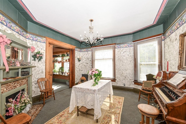 living area with wallpapered walls, baseboards, carpet flooring, a fireplace, and a notable chandelier