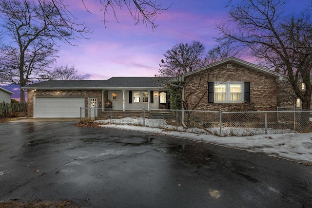 view of front of property with aphalt driveway, brick siding, a fenced front yard, and a garage