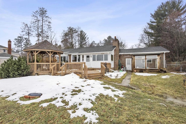 snow covered house featuring a wooden deck, a chimney, and a gazebo