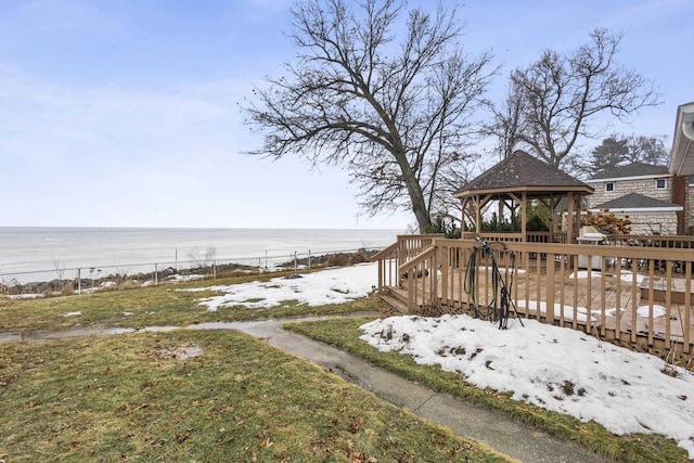 exterior space with fence, a deck with water view, and a gazebo