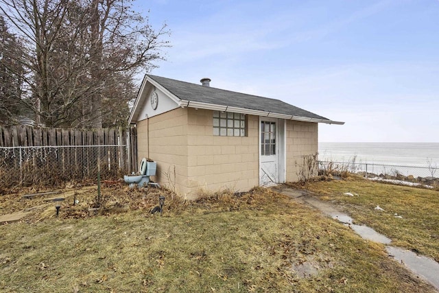 view of outbuilding with a water view, fence, and an outbuilding