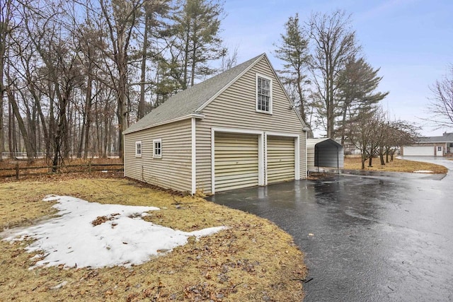 garage featuring aphalt driveway and a detached carport