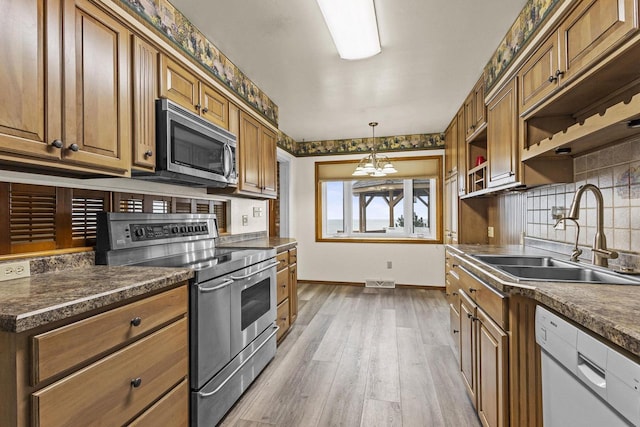 kitchen with appliances with stainless steel finishes, dark countertops, a sink, and open shelves