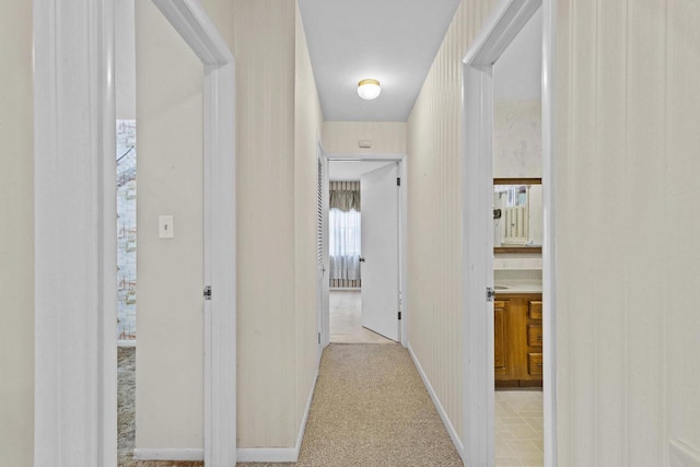 corridor featuring light carpet and baseboards