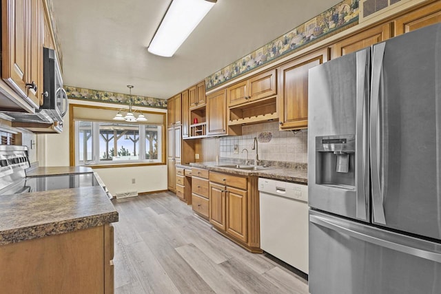 kitchen with a sink, appliances with stainless steel finishes, open shelves, light wood finished floors, and tasteful backsplash