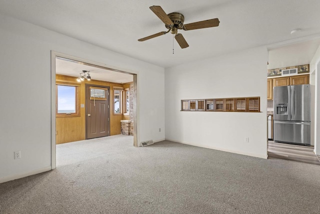 unfurnished living room featuring light colored carpet, ceiling fan, visible vents, and baseboards