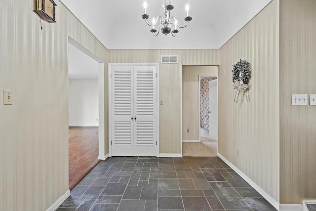 interior space featuring a notable chandelier, visible vents, baseboards, stone finish flooring, and wallpapered walls