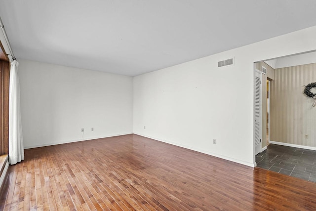 spare room with baseboards, visible vents, and hardwood / wood-style floors