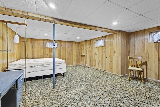 interior space with wood walls, carpet, and a drop ceiling