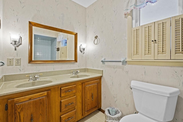 full bathroom featuring toilet, wallpapered walls, double vanity, and a sink