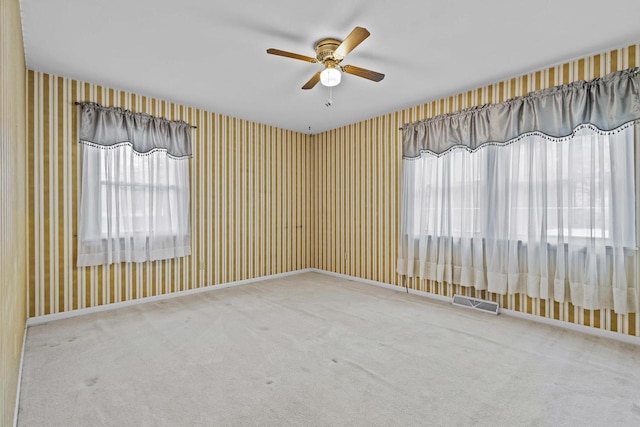 carpeted spare room with wallpapered walls, ceiling fan, visible vents, and baseboards