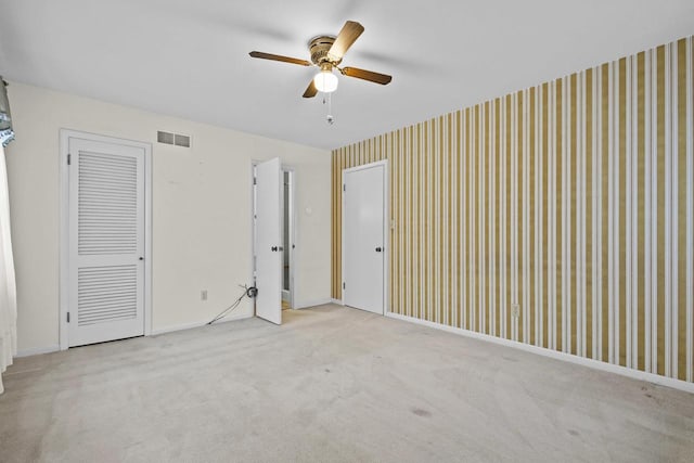 unfurnished bedroom featuring a ceiling fan, baseboards, visible vents, carpet, and wallpapered walls