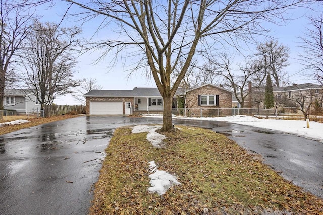 view of front facade with a garage, aphalt driveway, fence, and brick siding