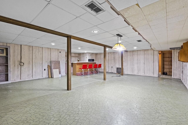 finished basement featuring recessed lighting, visible vents, wood walls, and a drop ceiling