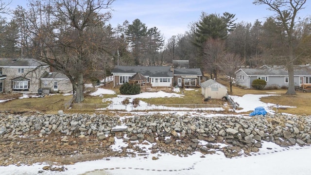 yard covered in snow with a storage unit, an outdoor structure, a wooden deck, and fence