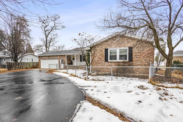 view of front of home with an attached garage, driveway, a fenced front yard, and brick siding