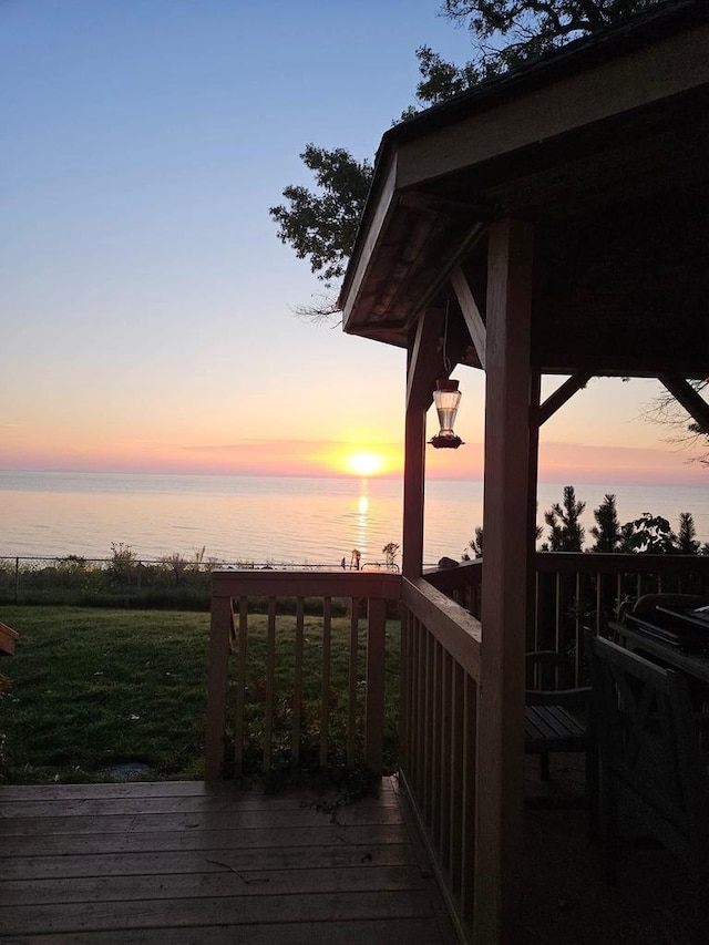 deck with a water view and a lawn