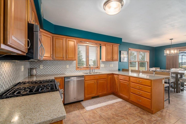 kitchen with stainless steel appliances, a peninsula, a sink, tasteful backsplash, and a kitchen bar