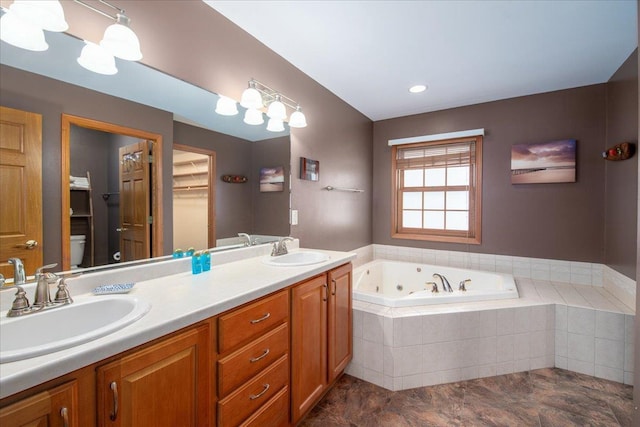 bathroom with toilet, a sink, a tub with jets, and double vanity