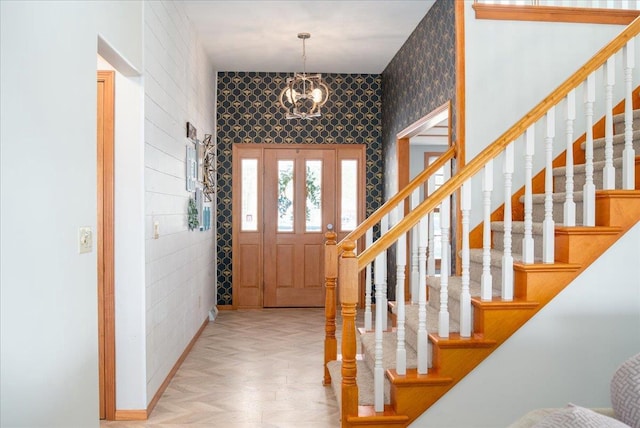 entrance foyer featuring stairs, a notable chandelier, and wallpapered walls