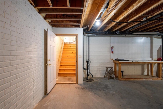 unfinished below grade area featuring brick wall and stairway