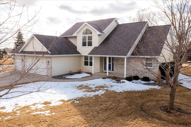 cape cod house with an attached garage, covered porch, brick siding, driveway, and roof with shingles