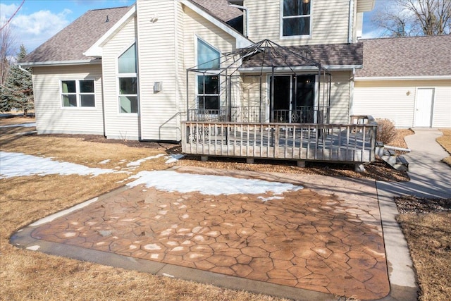 rear view of property featuring a shingled roof and a wooden deck