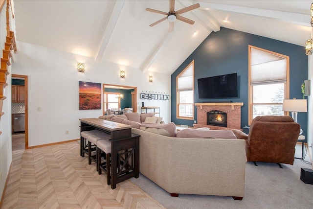 living area with baseboards, beamed ceiling, a fireplace, high vaulted ceiling, and ceiling fan with notable chandelier