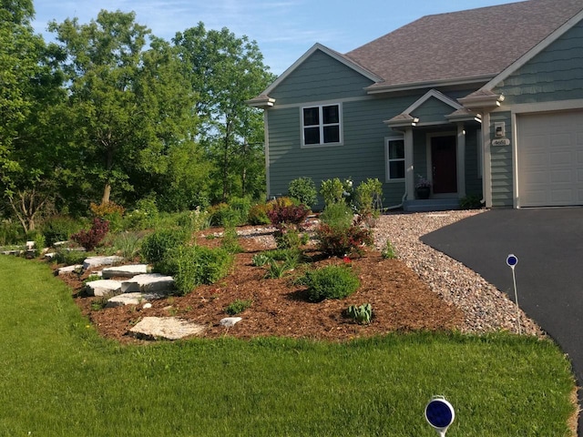 view of front of house featuring a garage, driveway, a shingled roof, and a front lawn