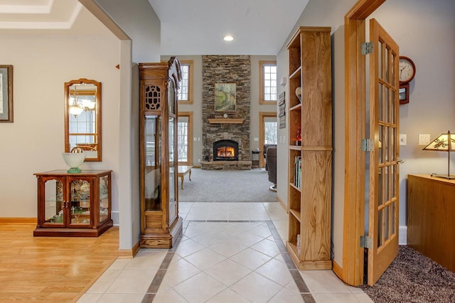 foyer with light tile patterned floors, recessed lighting, a high ceiling, a stone fireplace, and baseboards