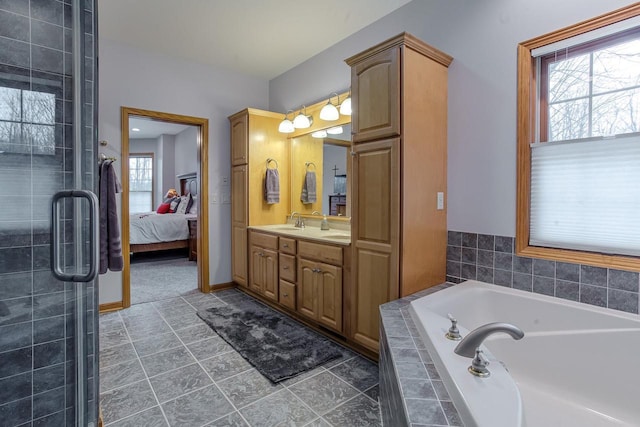 ensuite bathroom featuring connected bathroom, vanity, baseboards, tiled shower, and a bath