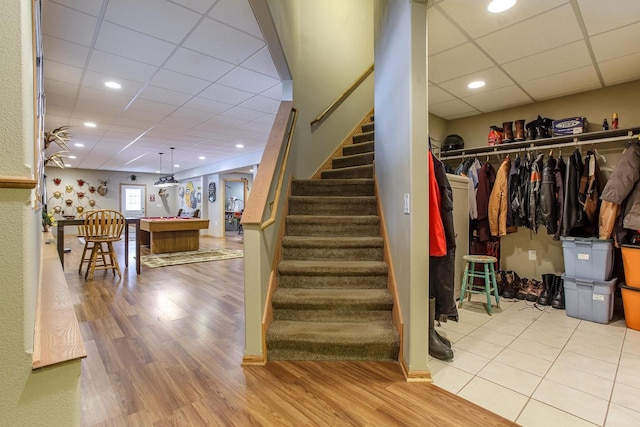 staircase with a paneled ceiling, wood finished floors, and recessed lighting