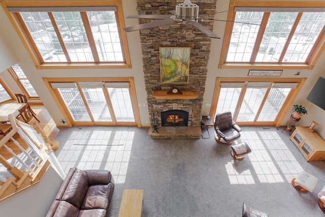 carpeted living room with a towering ceiling, ceiling fan, and a fireplace