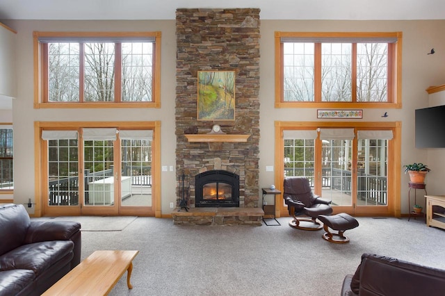 living room featuring carpet floors, a fireplace, and a towering ceiling