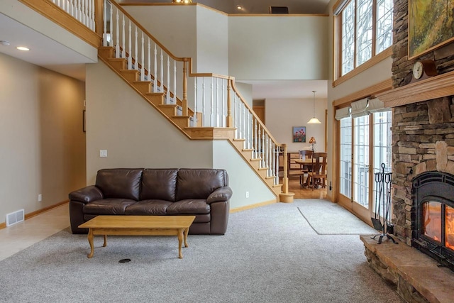 carpeted living area with stairway, a towering ceiling, visible vents, and baseboards