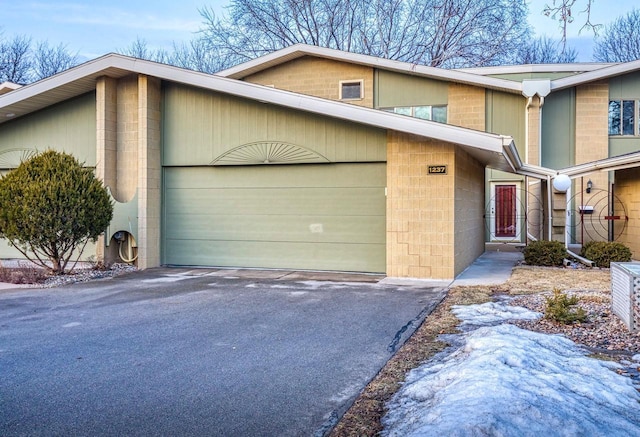 view of front of home featuring driveway, an attached garage, and concrete block siding