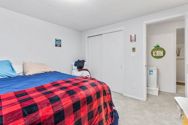 bedroom with light carpet, a closet, and baseboards