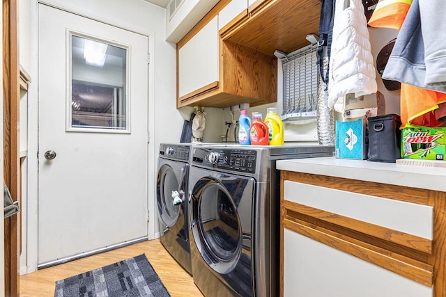 washroom with light wood-style floors, washing machine and dryer, and cabinet space