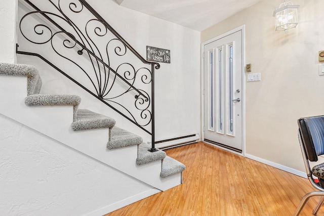 entrance foyer featuring a baseboard radiator, stairway, baseboards, and wood finished floors