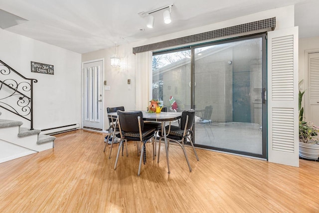 dining space with stairs, baseboard heating, and wood finished floors