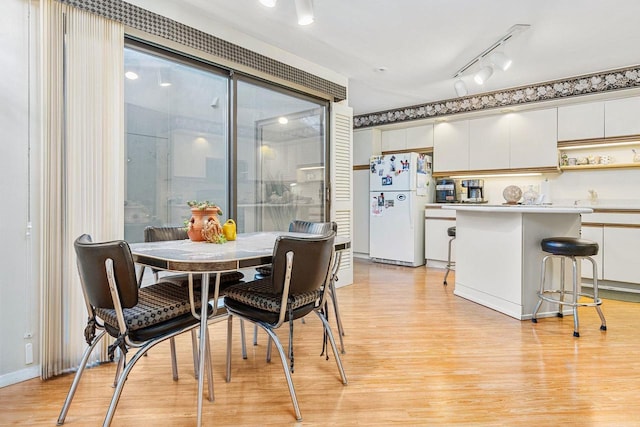 dining room with light wood finished floors and rail lighting