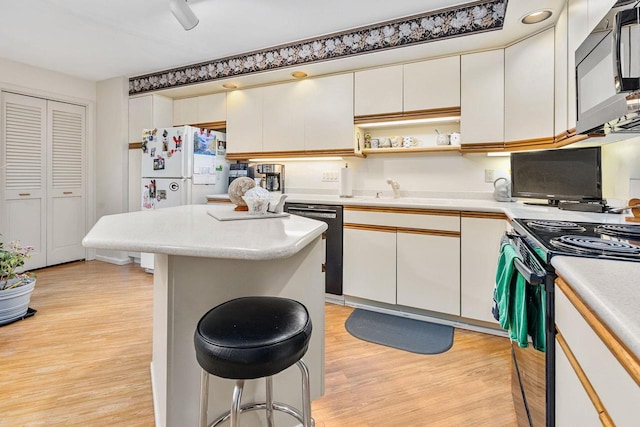 kitchen featuring light countertops, light wood finished floors, and black appliances