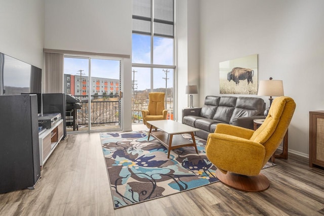 living area with baseboards, a high ceiling, wood finished floors, and a city view