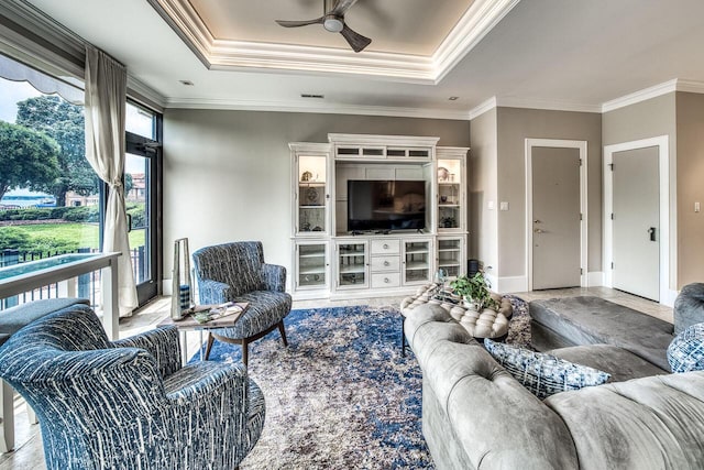 living room featuring a ceiling fan, a raised ceiling, crown molding, and baseboards