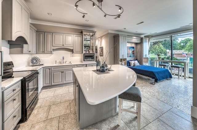 kitchen with a kitchen island, stainless steel microwave, black range with electric stovetop, crown molding, and a sink