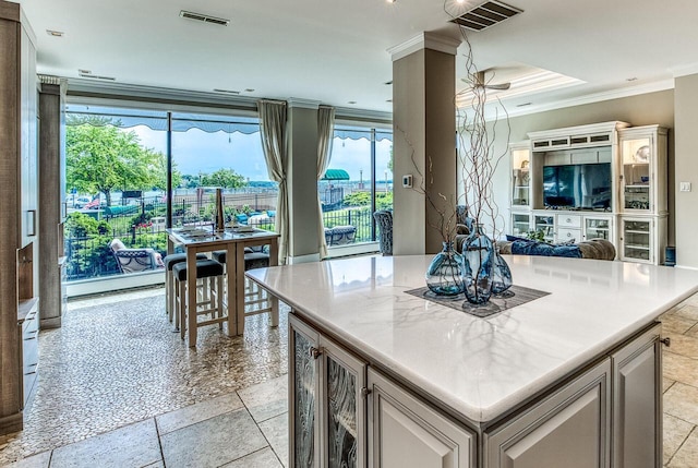 kitchen featuring open floor plan, visible vents, crown molding, and stone tile floors