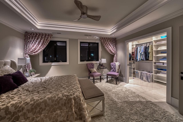 bedroom with a raised ceiling, crown molding, and a spacious closet