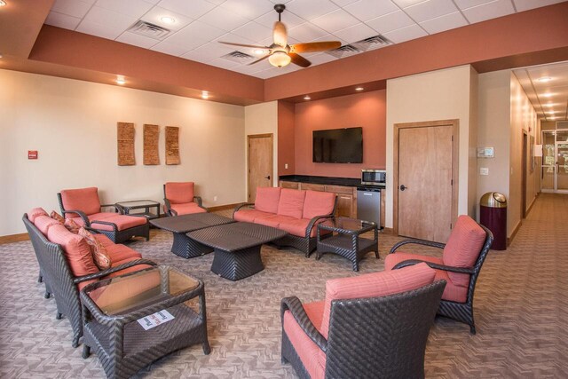 carpeted living room featuring a ceiling fan, a paneled ceiling, visible vents, and baseboards