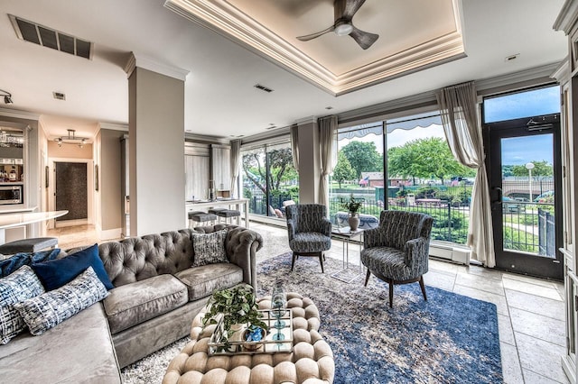 living room featuring ceiling fan, ornamental molding, a raised ceiling, and visible vents